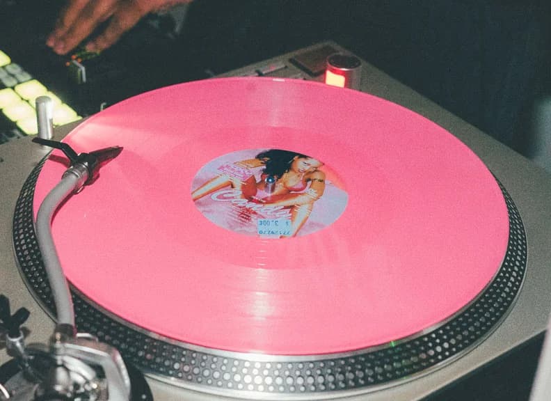 A pink-vinyl record spins on a turntable.