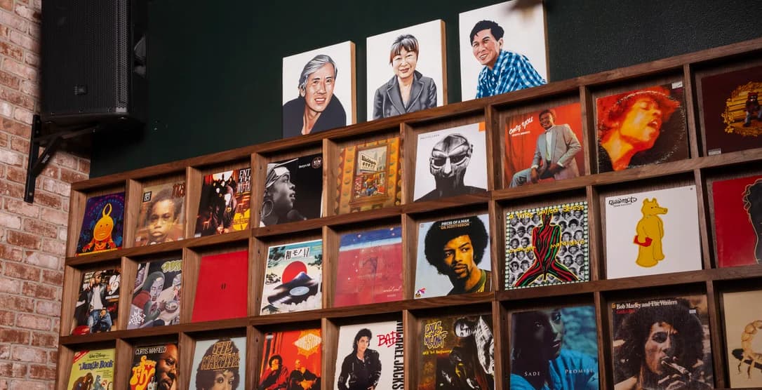 A wall of vinyl records beneath painted portraits, inside After Ours in Portland.